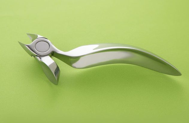 Quebra-nozes de metal polido com design moderno, em fundo verde.