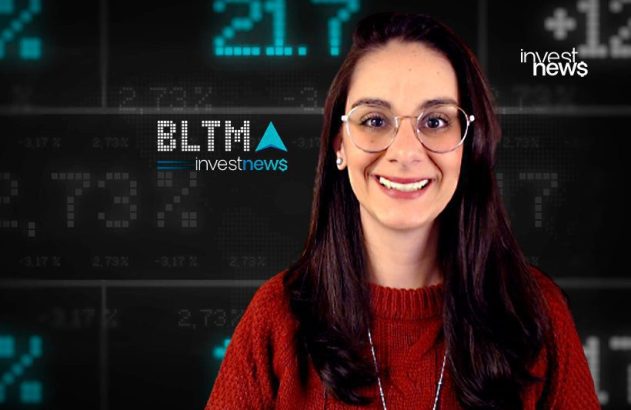 Mulher sorridente com óculos em frente a uma tela digital exibindo dados financeiros e logos "investnews".