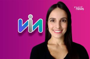 Mulher sorridente ao lado do logo Via (com 'i' humanoide) em fundo degradê roxo-rosa.