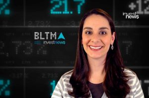 Mulher sorrindo em frente a painel com dados financeiros e logo Investnews.