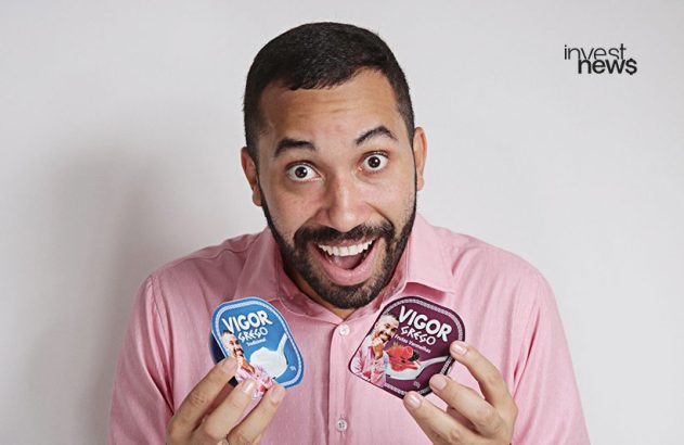 Homem sorridente e de olhos arregalados segura dois potes de iogurte "Vigor Grego" com sua própria foto.