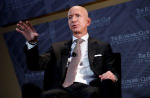 Dono da Amazon, Jeff Bezos, de terno, fala e gesticula sentado em evento do Economic Club.