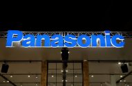 Letreiro grande e azul iluminado da marca Panasonic em um salão de exposição, com estrutura metálica aparente.
