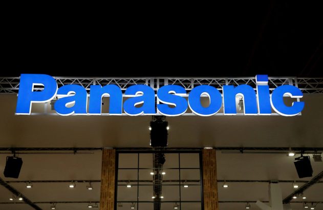 Letreiro grande e azul iluminado da marca Panasonic em um salão de exposição, com estrutura metálica aparente.