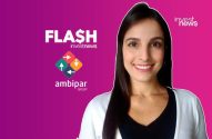 Apresentadora sorridente de 'FLASH investnews' e 'investnews' com logotipos 'ambipar Group' em fundo roxo.