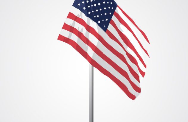 Bandeira dos Estados Unidos de mesa, erguida em mastro com base, contra um fundo claro e liso.