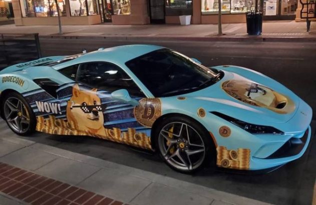 Carro esportivo azul-claro com envelopamento temático Dogecoin, apresentando o meme Doge e moedas douradas. Estacionado na rua.