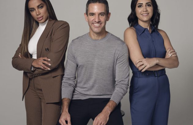 Retrato de três pessoas em estúdio: duas mulheres e um homem sorrindo para a câmera. Estão em roupas profissionais.