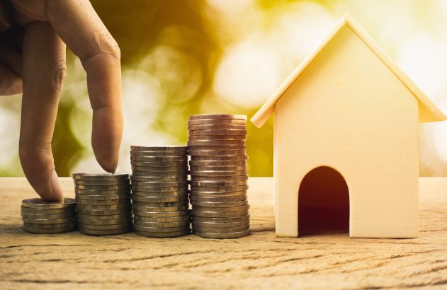 Pilhas de moedas ao lado de uma casa