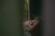 Mulher deitada, dormindo em um ambiente escuro, parcialmente obscurecida.