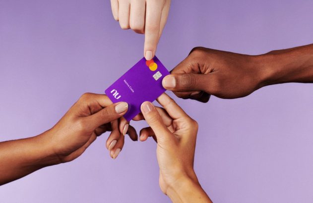 Mãos de diversas etnias interagem com um cartão roxo Nubank, um dedo aponta para ele.