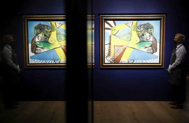 Pinturas de Picasso em exposição, guardas mascarados com luvas em galeria escura, separados por painel refletivo.