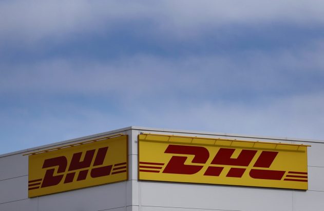 Dois grandes sinais amarelos e vermelhos da DHL no canto de um prédio, sob um céu azul claro.