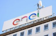 Letreiro "Enel" colorido no topo de um edifício com antenas, sob céu azul claro.