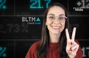 Mulher sorrindo com óculos faz sinal de V. Fundo digital com dados de mercado e logos BLTMA e investnews.