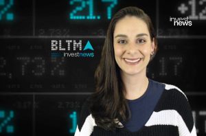 Mulher sorrindo em frente a um painel com dados financeiros e o logo "investnews".