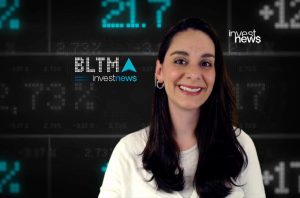 Mulher sorridente em frente a um painel digital com dados financeiros e os logos "investnews" e "BLTMA".