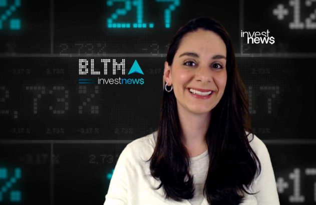 Mulher sorridente em frente a um painel digital com dados financeiros e os logos "investnews" e "BLTMA".