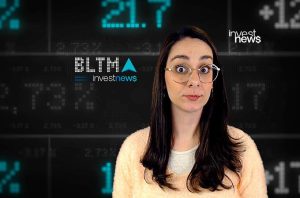 Mulher com óculos e olhos arregalados em estúdio de notícias financeiras, com números e o logo InvestNews ao fundo.