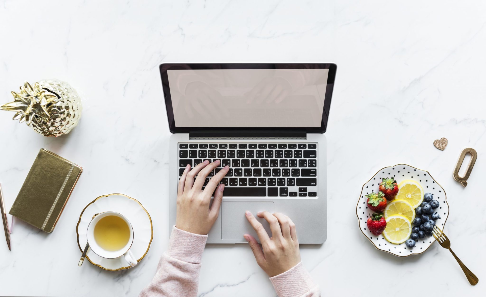 mãos femininas com um laptop em uma mesa com frutas