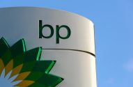 Sinal branco da BP com logo verde e amarelo e letras 'bp' verdes, sob céu azul.