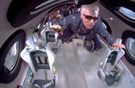 Richard Branson flutua em microgravidade na cabine de uma nave espacial. Outras pessoas e assentos.