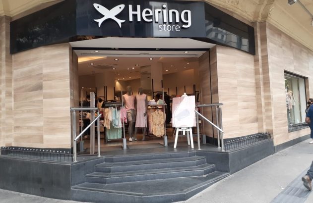 Fachada da Hering store: letreiro com logo e nome, entrada com degraus, roupas em manequins.