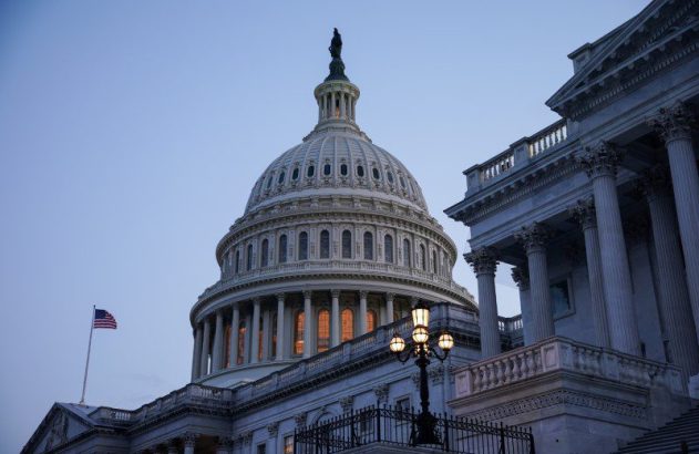 A cúpula iluminada do Capitólio dos EUA ao anoitecer, com a bandeira americana e um lampião.