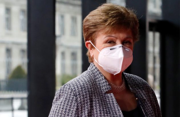 Mulher de cabelo castanho, máscara branca e casaco estampado, olhando à frente.