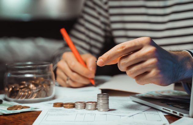 Mão de pessoa segurando lápis fazendo cálculo do imposto de renda