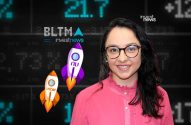 Mulher sorri em frente a tela digital de mercado financeiro com foguetes do Nu e Inter. InvestNews.
