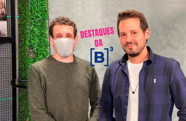 Dois homens posam para 'DESTAQUES DA [B]³'. Um usa máscara, o outro tem barba, em frente a uma parede verde.