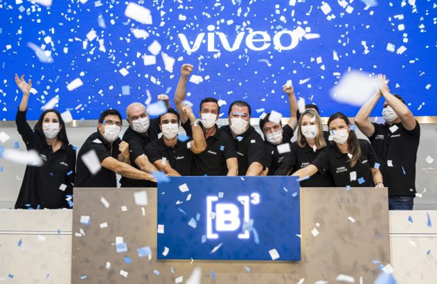 Grupo com máscaras celebra evento da Viveo na B3 com confetes.