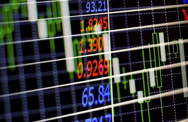 Tela digital exibe dados financeiros com números coloridos, gráficos de velas e linhas de grade em um fundo escuro.