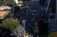 Vista aérea de rua cheia de pessoas em verde e amarelo durante uma manifestação em cidade brasileira.