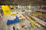 Grande centro de distribuição do Mercado Livre com trabalhadores movimentando caixas e produtos em diversas áreas de logística.