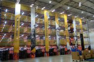 Centro de distribuição com prateleiras cheias de caixas, banners "infra.commerce" e uma empilhadeira em operação.