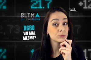 Mulher pensativa questiona "AGRO VAI MAL MESMO?" em frente a uma tela digital com dados financeiros e logos Investnews.