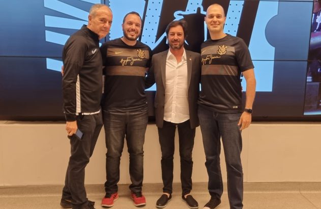 Quatro homens sorridentes, incluindo dois com camisas Ayrton Senna, posam em evento.