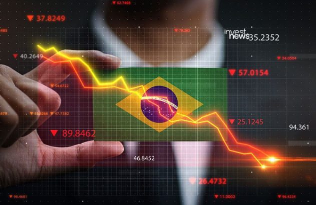Mão sobre dados econômicos digitais da bandeira do Brasil, mostrando indicadores em queda. (88 caracteres)