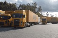 Frota de caminhões amarelos de carga (Sedex, Correios) em pátio de logística.