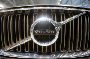 Detalhe da grade frontal de um carro Volvo com o logotipo cromado da marca.