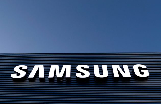 Letreiro branco da Samsung em fachada escura sob céu azul.