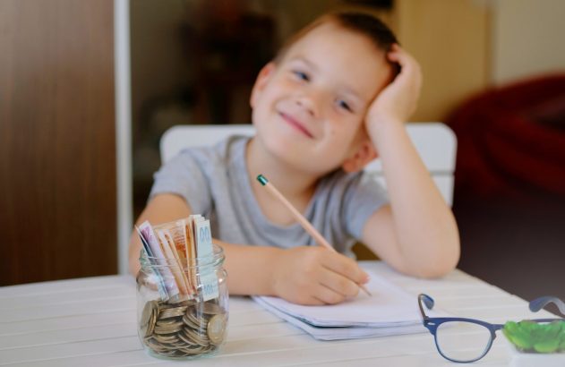 Criança fazendo as contas e guardando dinheiro