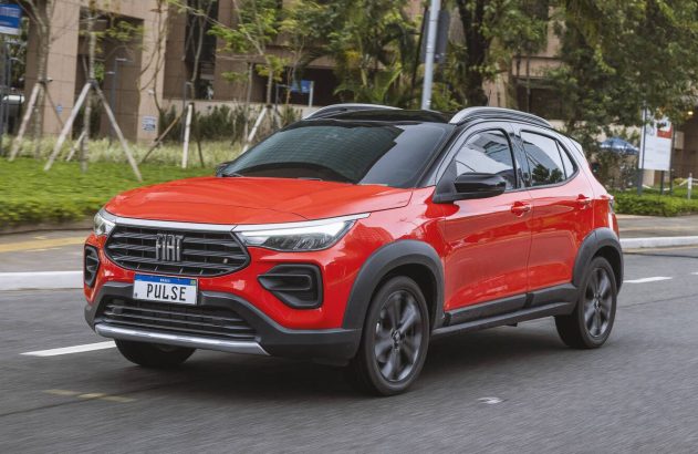 Fiat Pulse vermelho (SUV) em movimento em rua urbana. Prédios e árvores ao fundo.