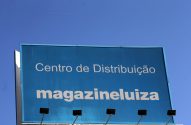 Um outdoor azul exibe "Centro de Distribuição magazineluiza" sob um céu claro.