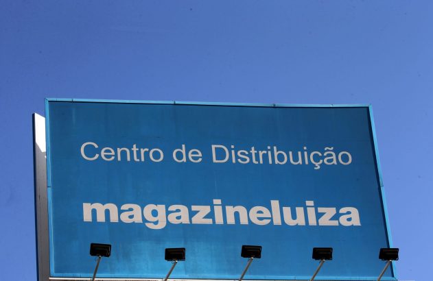 Um outdoor azul exibe "Centro de Distribuição magazineluiza" sob um céu claro.