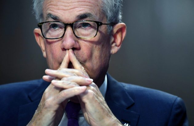 Homem de óculos, cabelos grisalhos, terno azul. Mãos unidas sob o queixo, olhando pensativo.