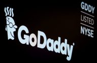 Logo GoDaddy e seu mascote em tela escura, com o ticker GDDY e 'LISTED NYSE', indicando a listagem na bolsa.