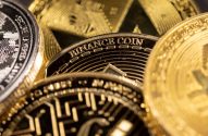 Close-up de várias moedas digitais douradas e prateadas, com "BINANCE COIN" visível em uma delas.